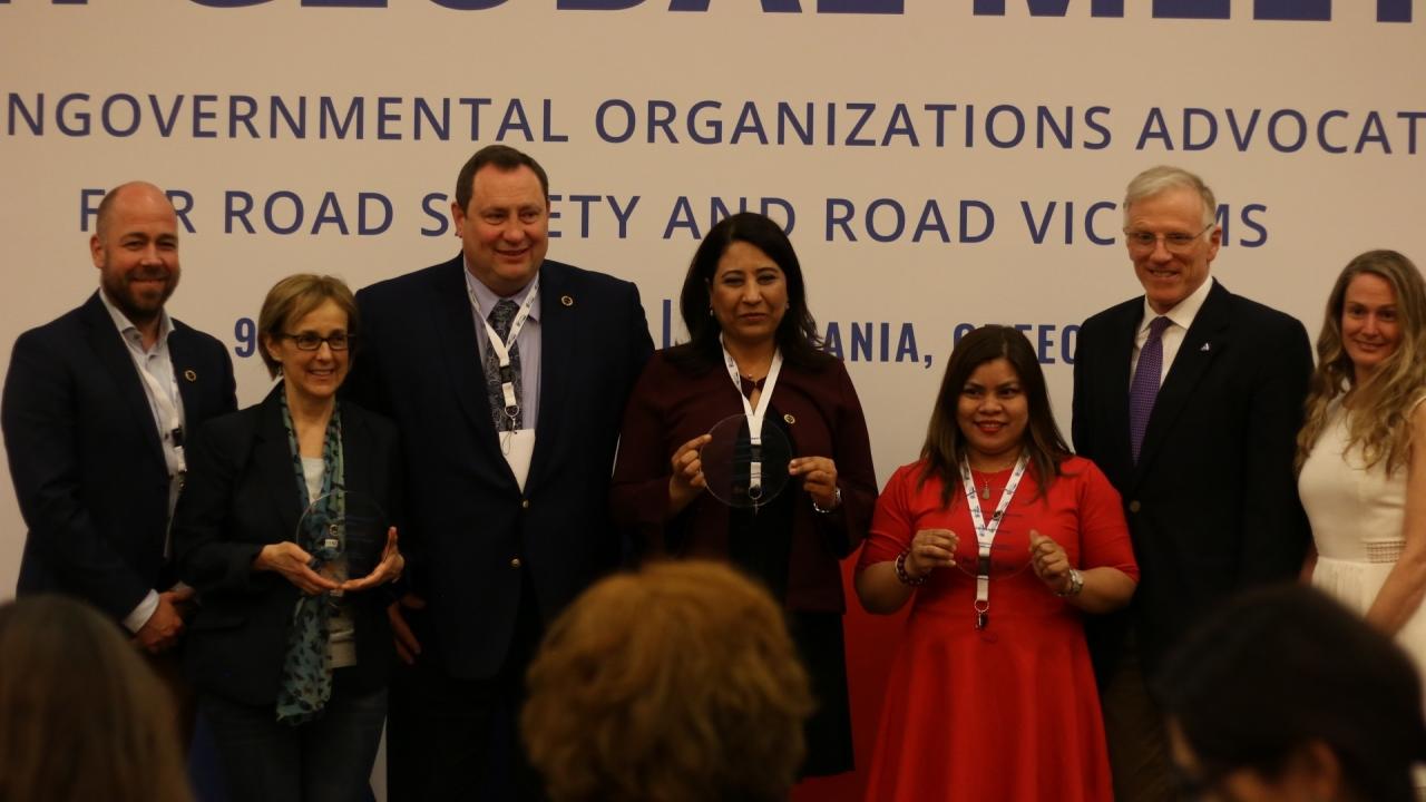 A group of people posing for a folder with 3 holding awards