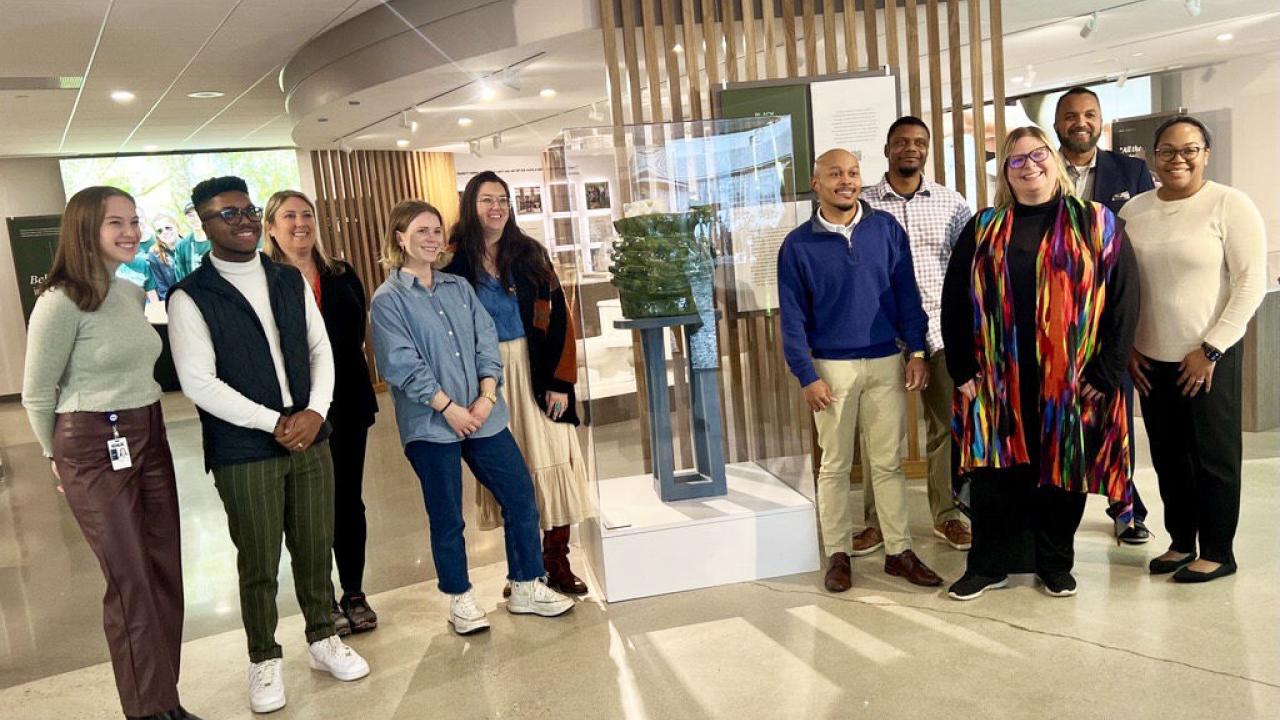 A group of people posed by a sculpture in a gallery.