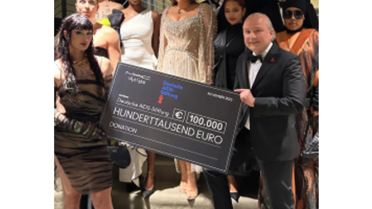 A group posed on a staircase, two holding a large check.