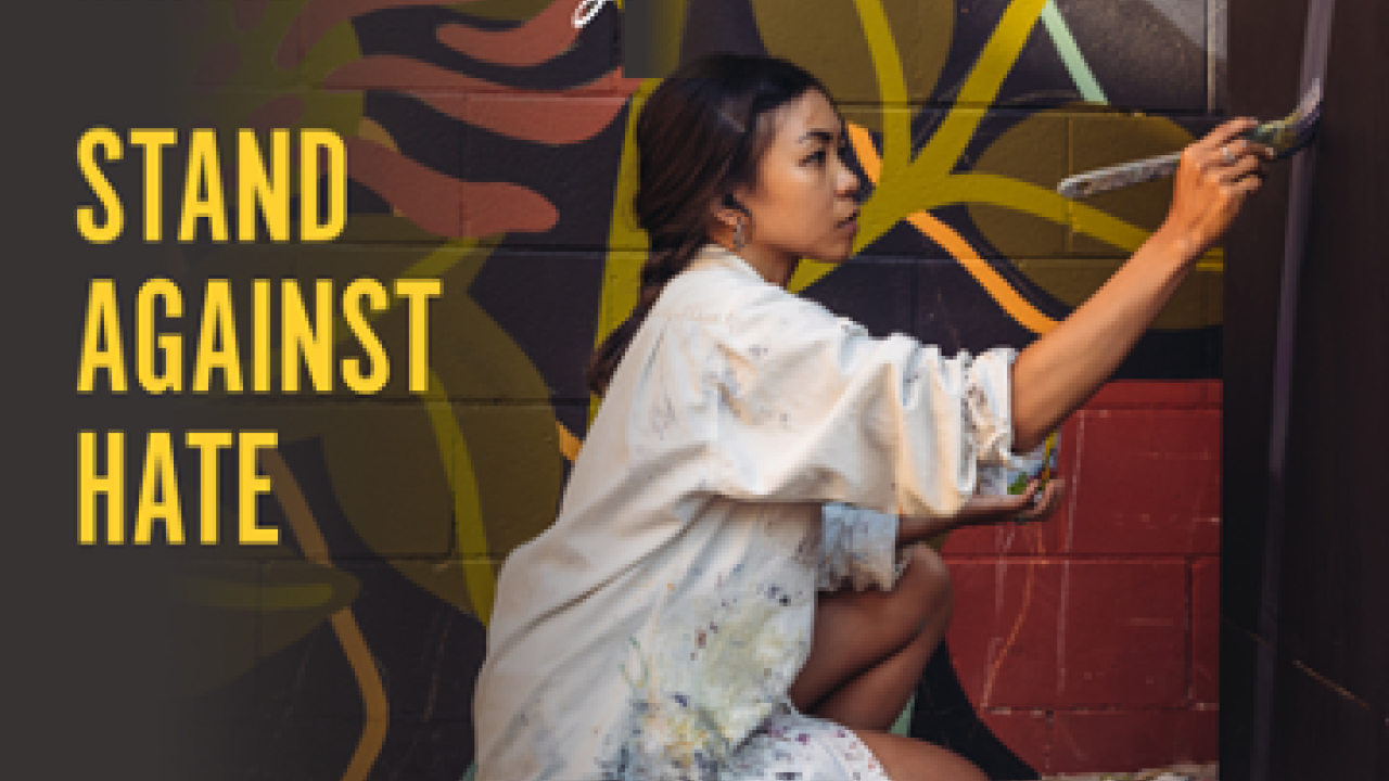 Banner with image of muralist painting and the words, "Stand Against Hate"