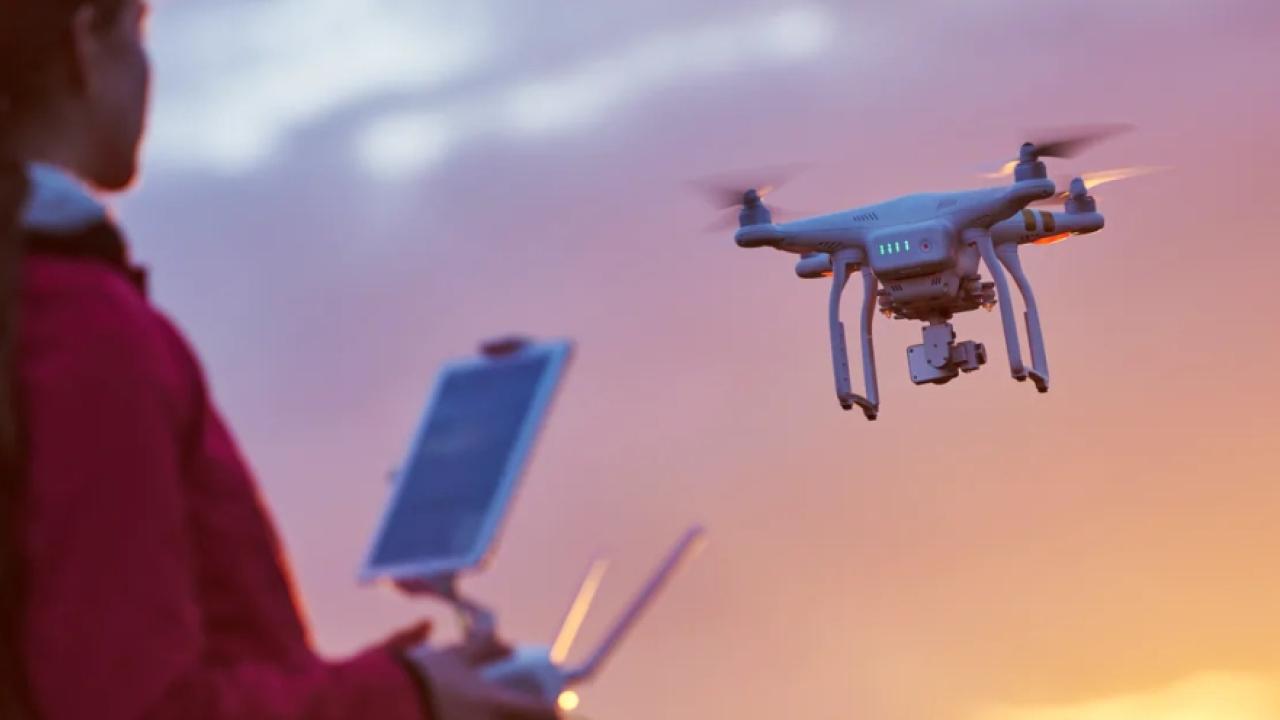a person flys a drone, sun setting in the background