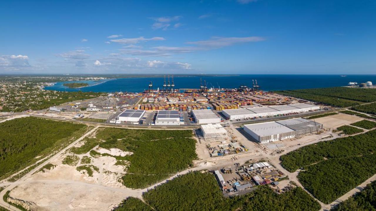An expansive aerial view of DP World’s Caucedo Port and Special Economic Zone in the Dominican Republic, showing container yards, cranes, logistics warehouses, and surrounding greenfield development along the coastline.