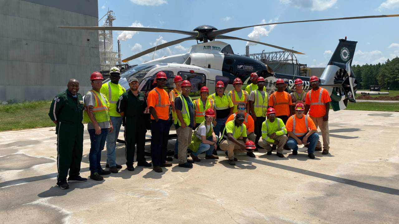 A group of people posing for a photo in front of a helicopter 
