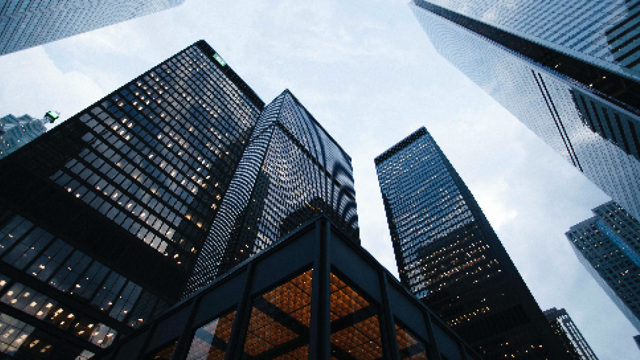 Photo looking up at the sky through a group of skyscrapers.