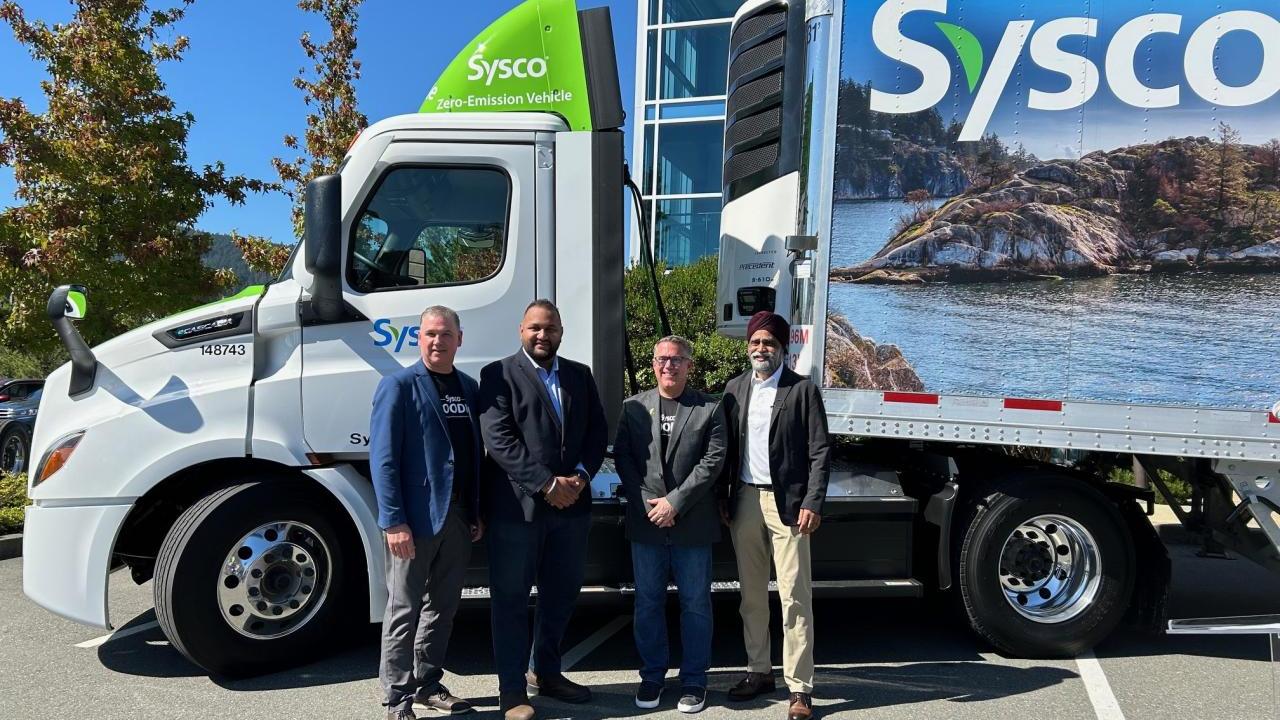 Four people standing by a Sysco semi truck