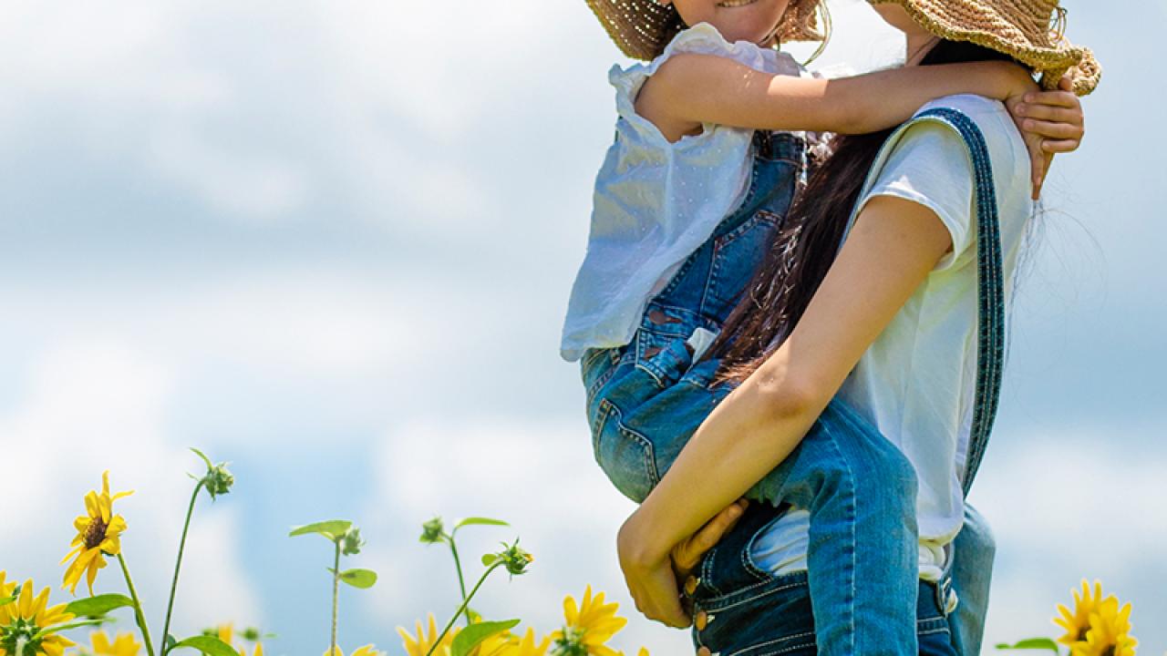 Person holding child in sunflower field