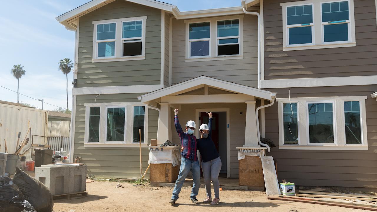 Cynthia E., her husband Valdemar C. pose outside of their new home by Habitat