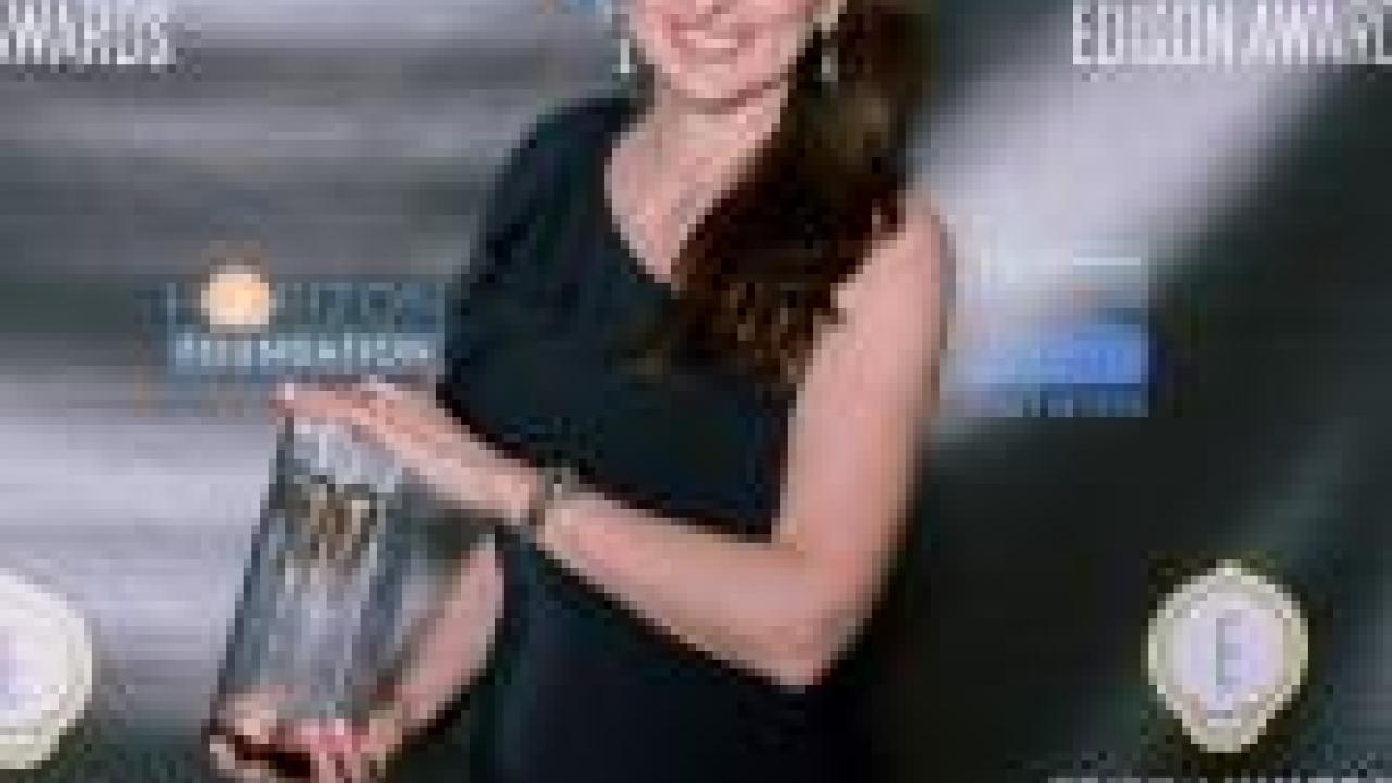 A person holds a trophy in front of a black backdrop with 'Edison Award' logos