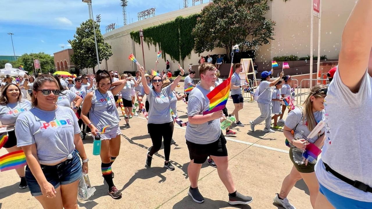 People marching in a parade, carrying rainbow flags