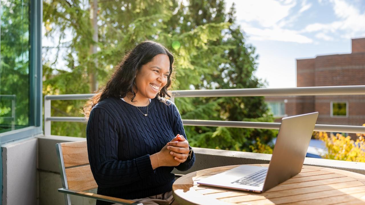 GoDaddy employee sitting outside with a laptop.