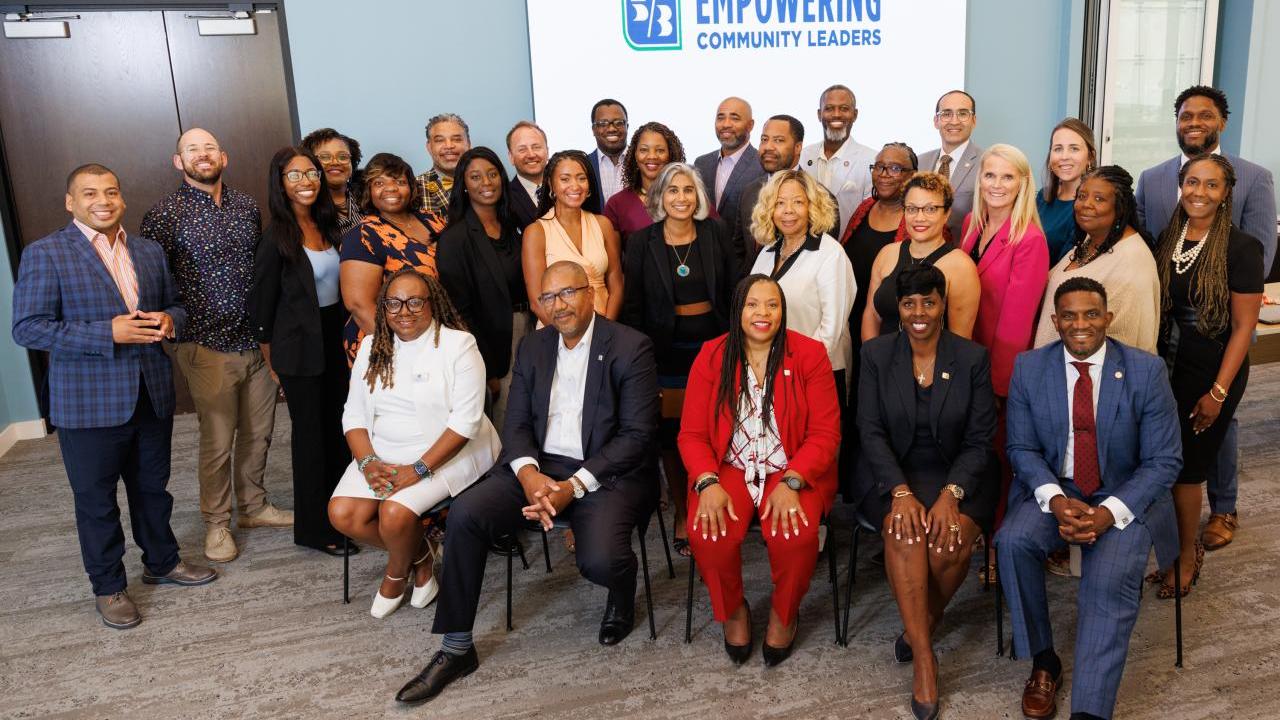 group of people smiling in front of Empowering Community Leaders sign