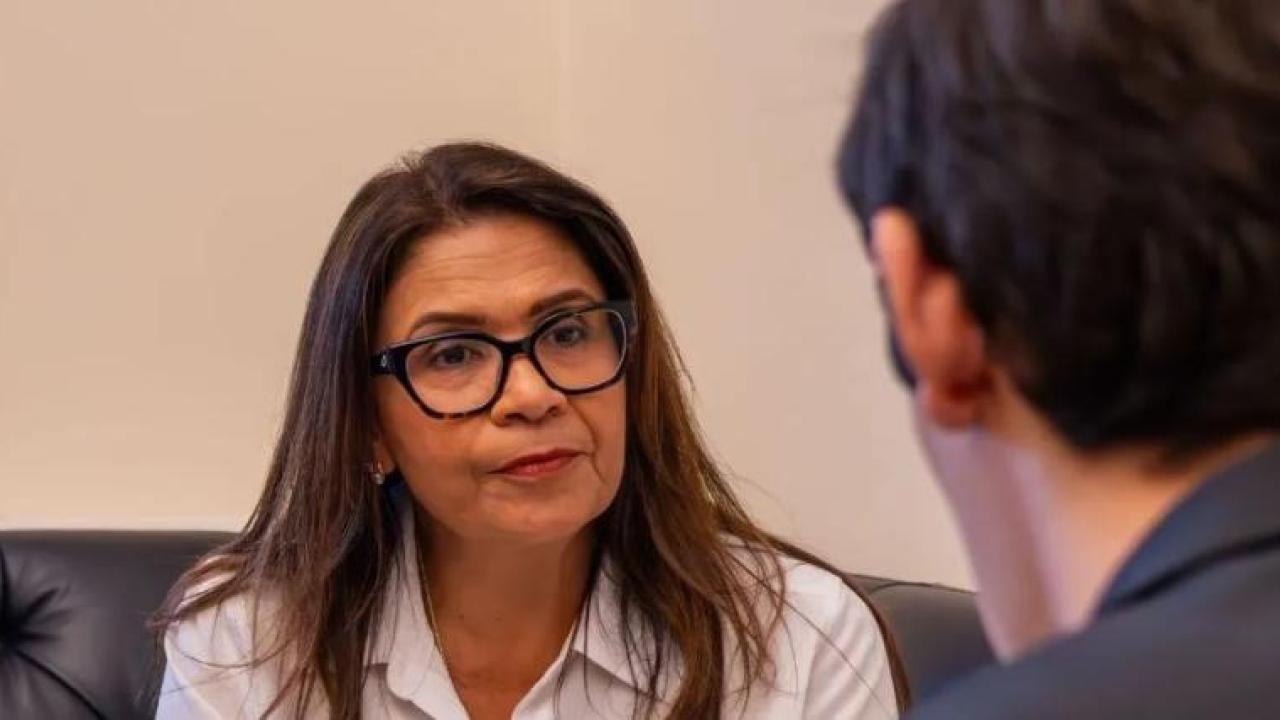 Woman wearing glasses speaking to someone on a couch