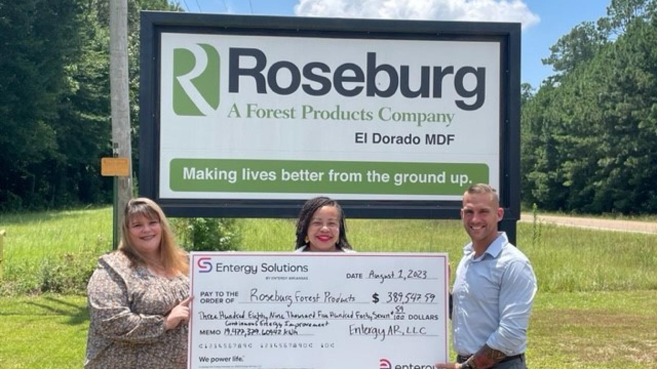 3 people holding a big check in front of a Roseburg sign