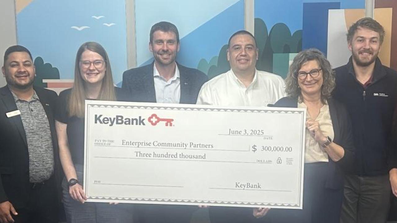 Representatives from KeyBank and Enterprise Community Partners shown with a grant check for $300,000.