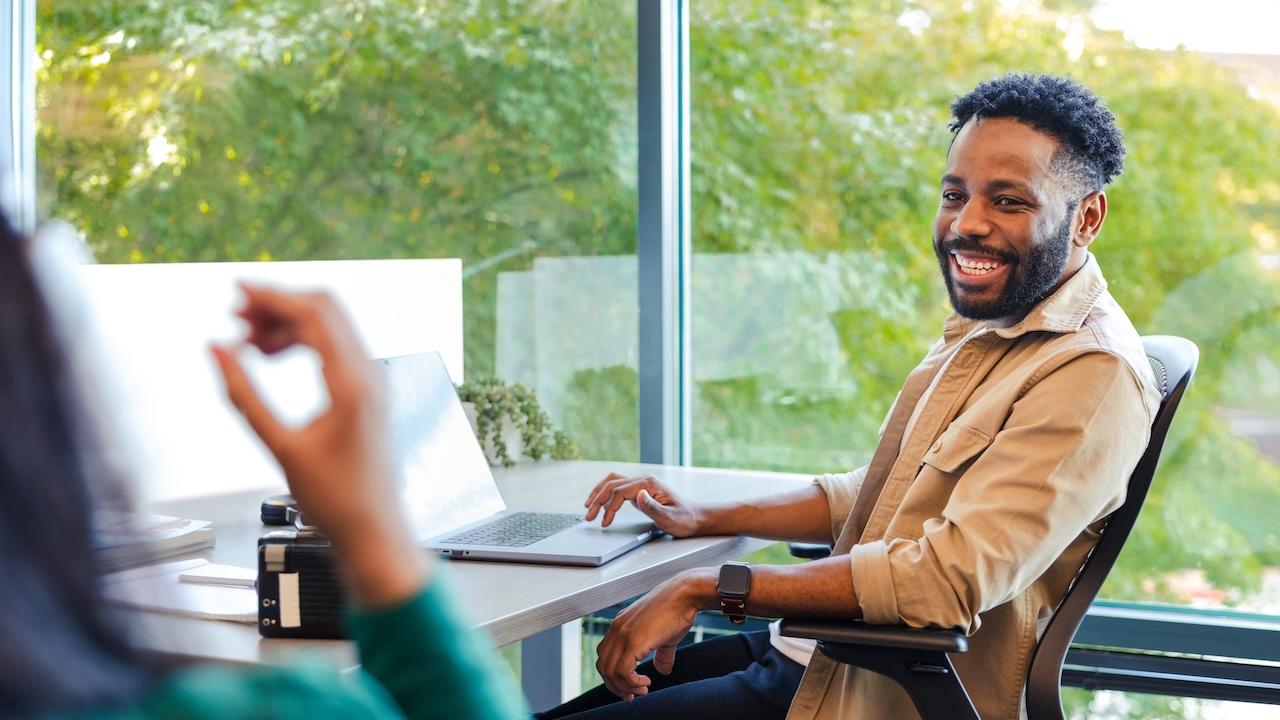 GoDaddy Team Member seated at a desk by a glass window.