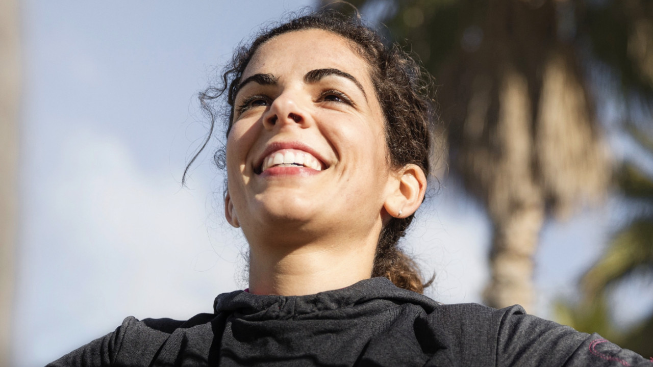 Young woman smiling with her arms outstretched.