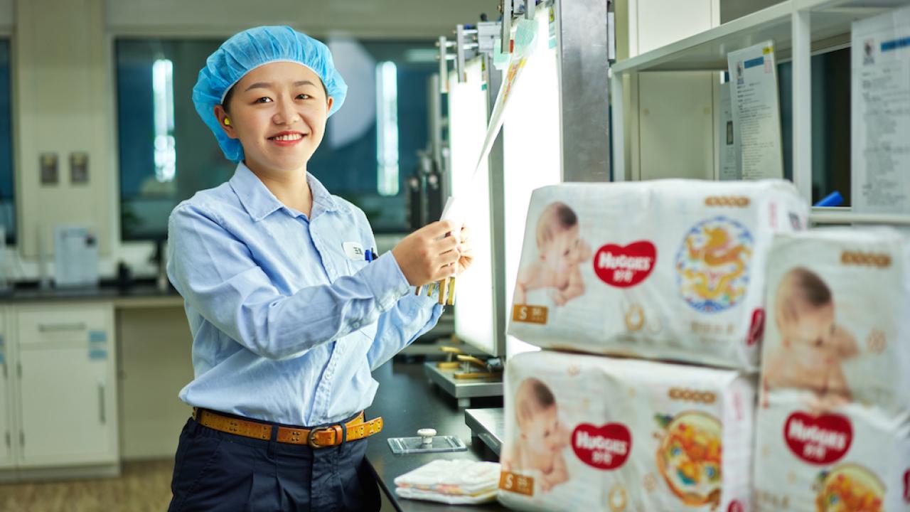 Kimberly-Clark employee standing next to Huggies diapers