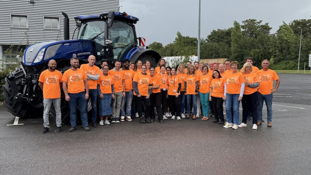 Group photo of participants in orange shirts in front of large tractor