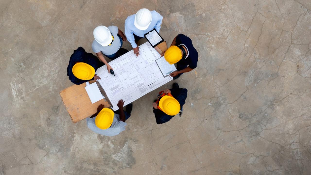 Aerial view of engineers around a table with a blueprint