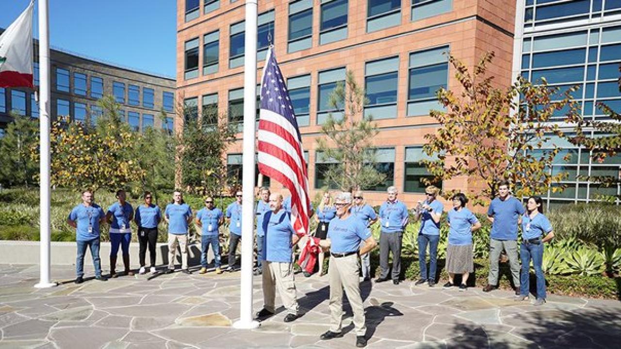 employees standing outside near American flag