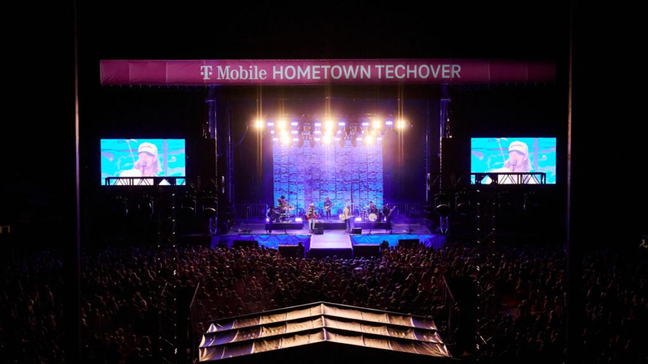 aerial view of a lit up concert stage, two monitors on the sides