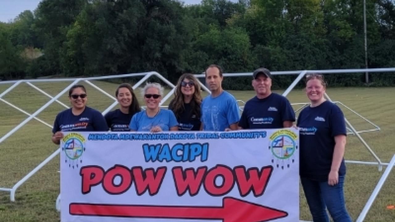 Employees holding a wacipi pow-wow banner