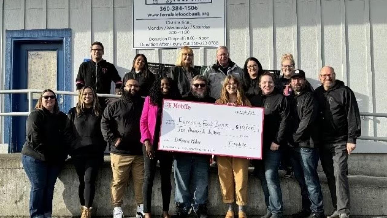 A group of people stood outside Ferndale Food Bank, holding a donation cheque