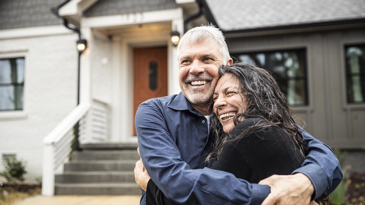 Young couple hugging in front of their new home.
