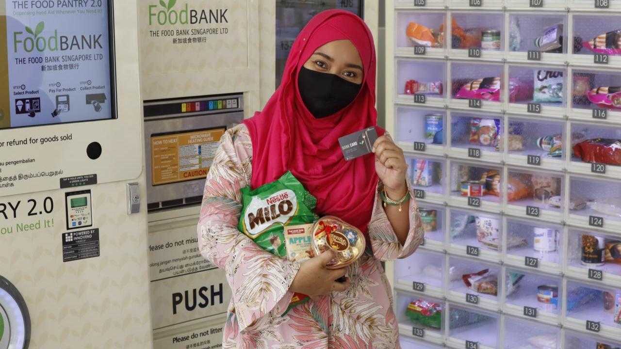 Woman holding up her food bank card