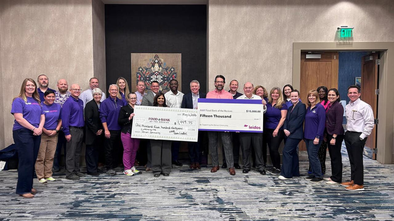 Group photo with two large checks on display for the food bank