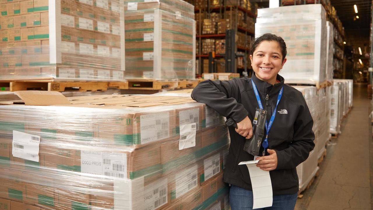 person smiling next to a warehouse of boxes