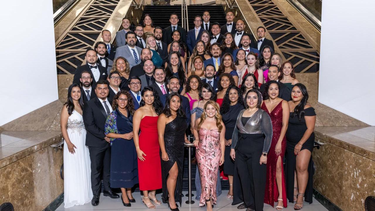 More than 50 people standing at the base of stairs wearing formal attire