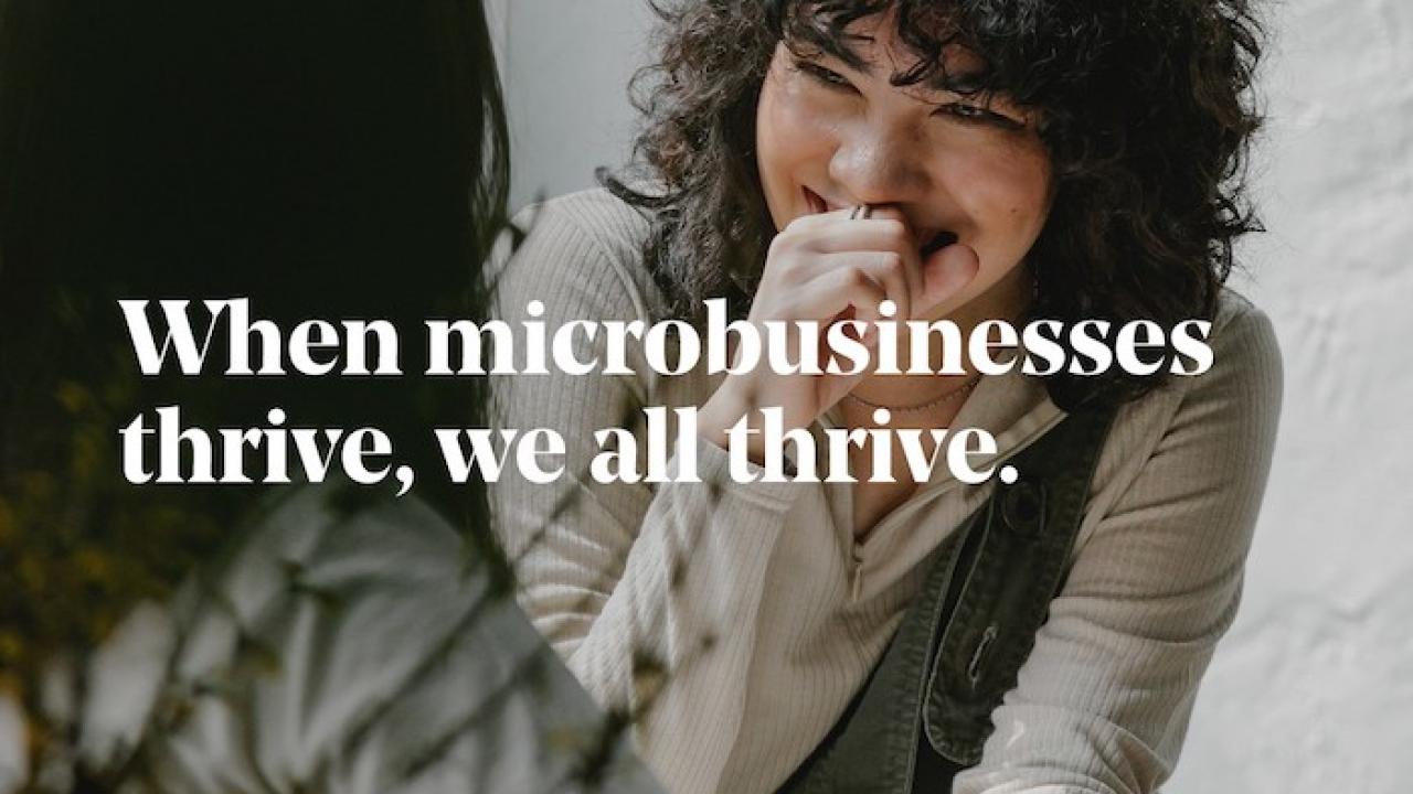 GoDaddy: Venture Forward. When microbusinesses thrive, we all thrive. Photo of two women seated at a small table.