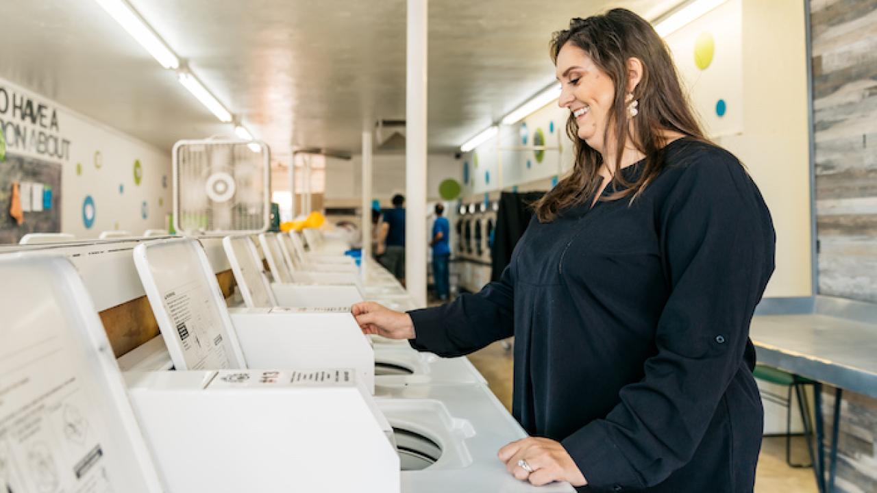 Christy Moore, Social Spin Laundromat AEO in Partnership; standing in a laundromat.