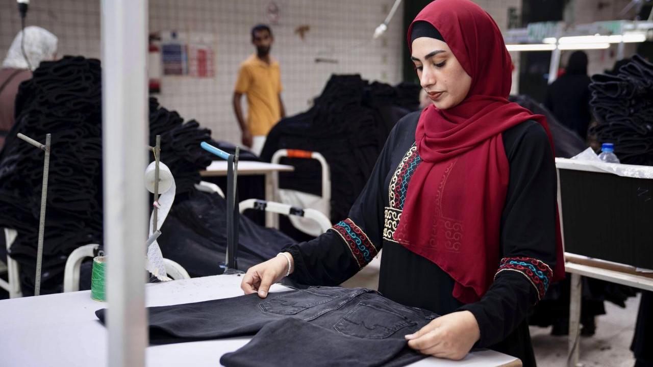 A garment worker folding a pair of jeans