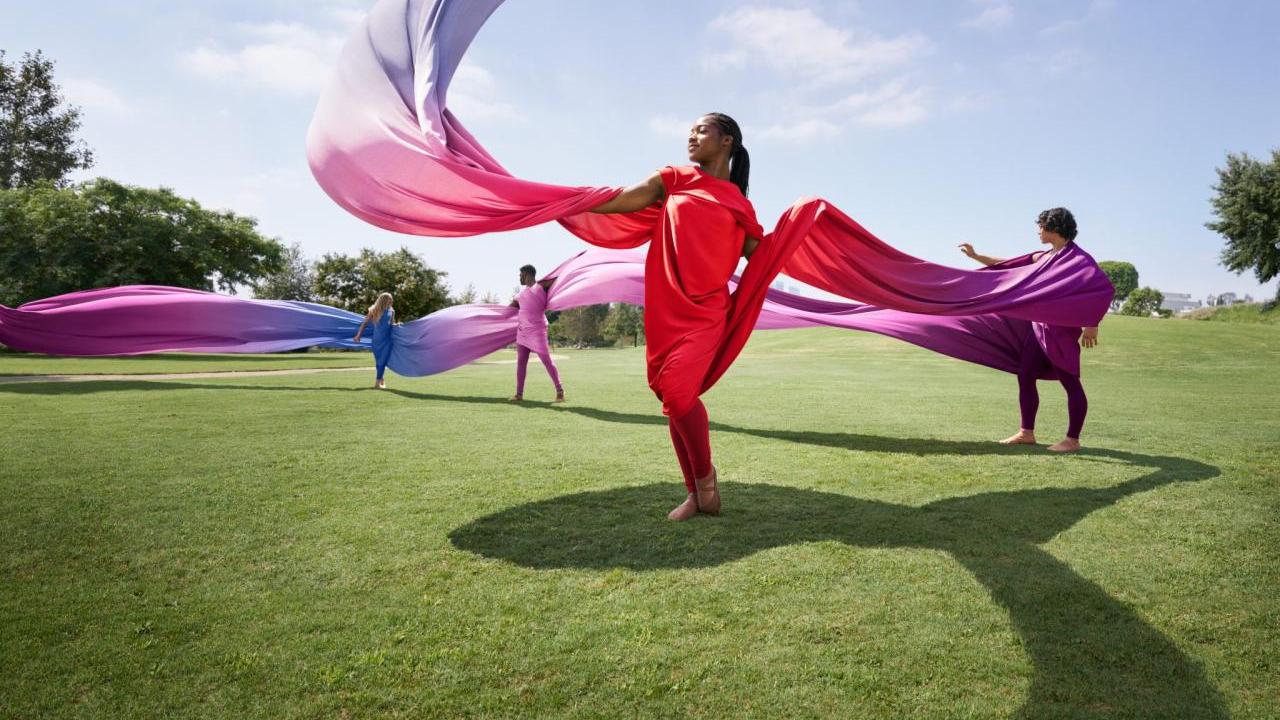 women dancing with colorful fabric on a lawn