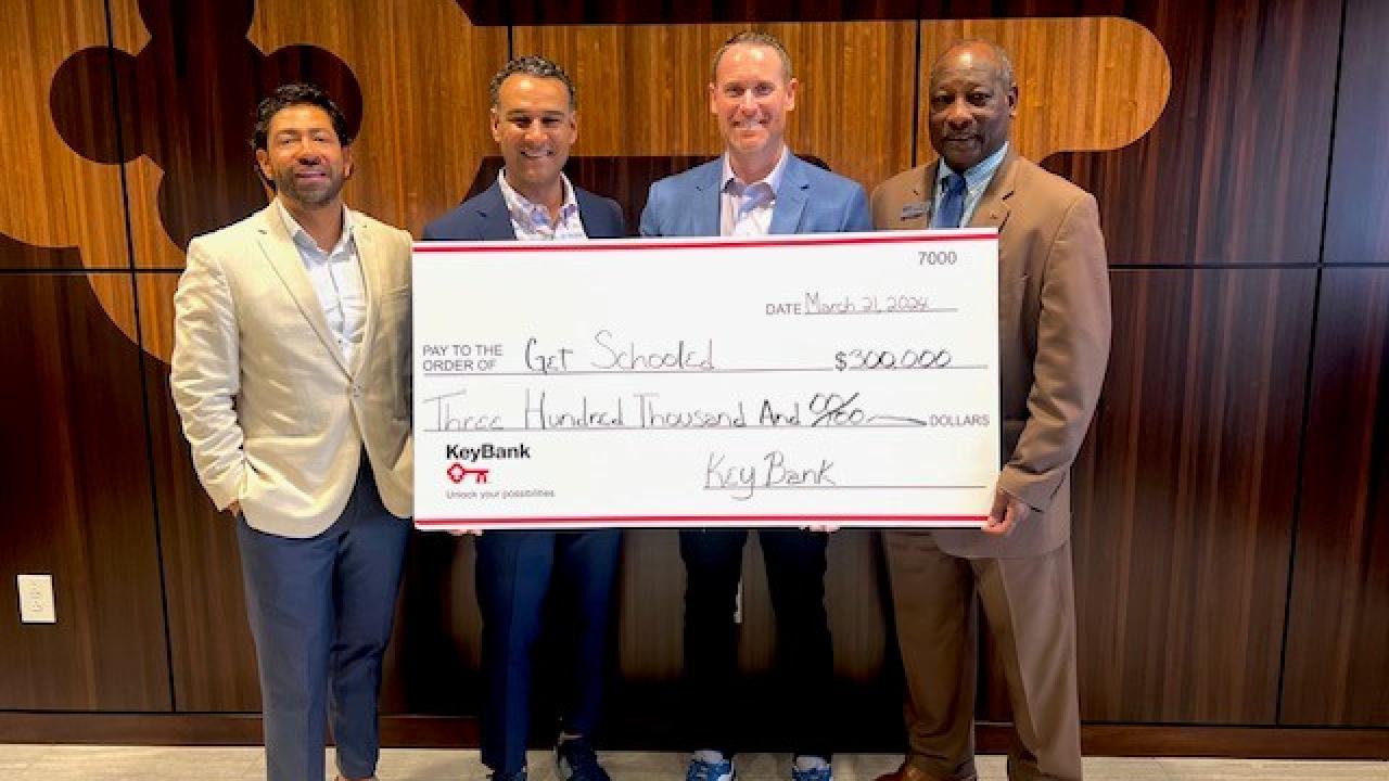 Get Schooled - people smiling with large check