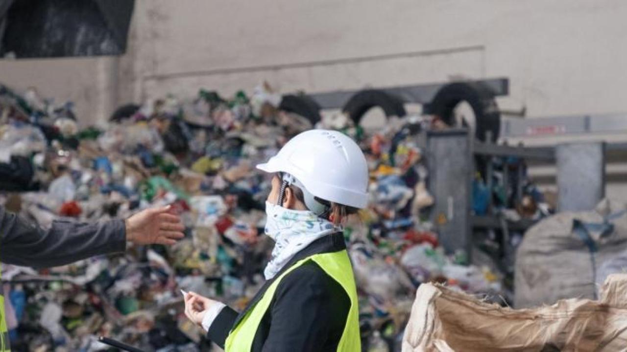 Two workers speaking in front of a landfill