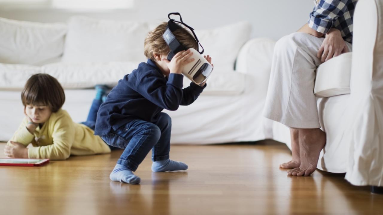 Children playing with VR headset and tablet in front of parent
