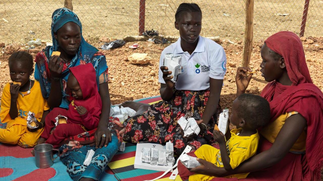 Mothers and children receiving care from Action Against Hunger worker