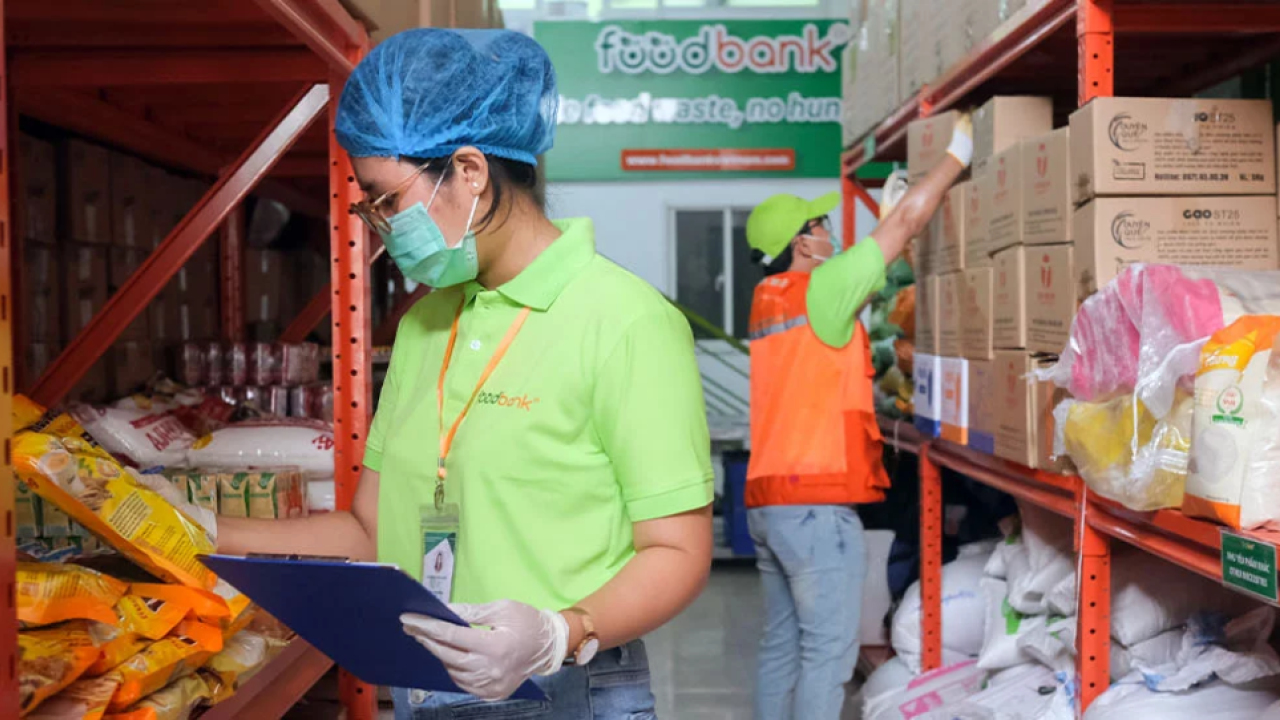 two workers in ppe collecting food items from a warehouse