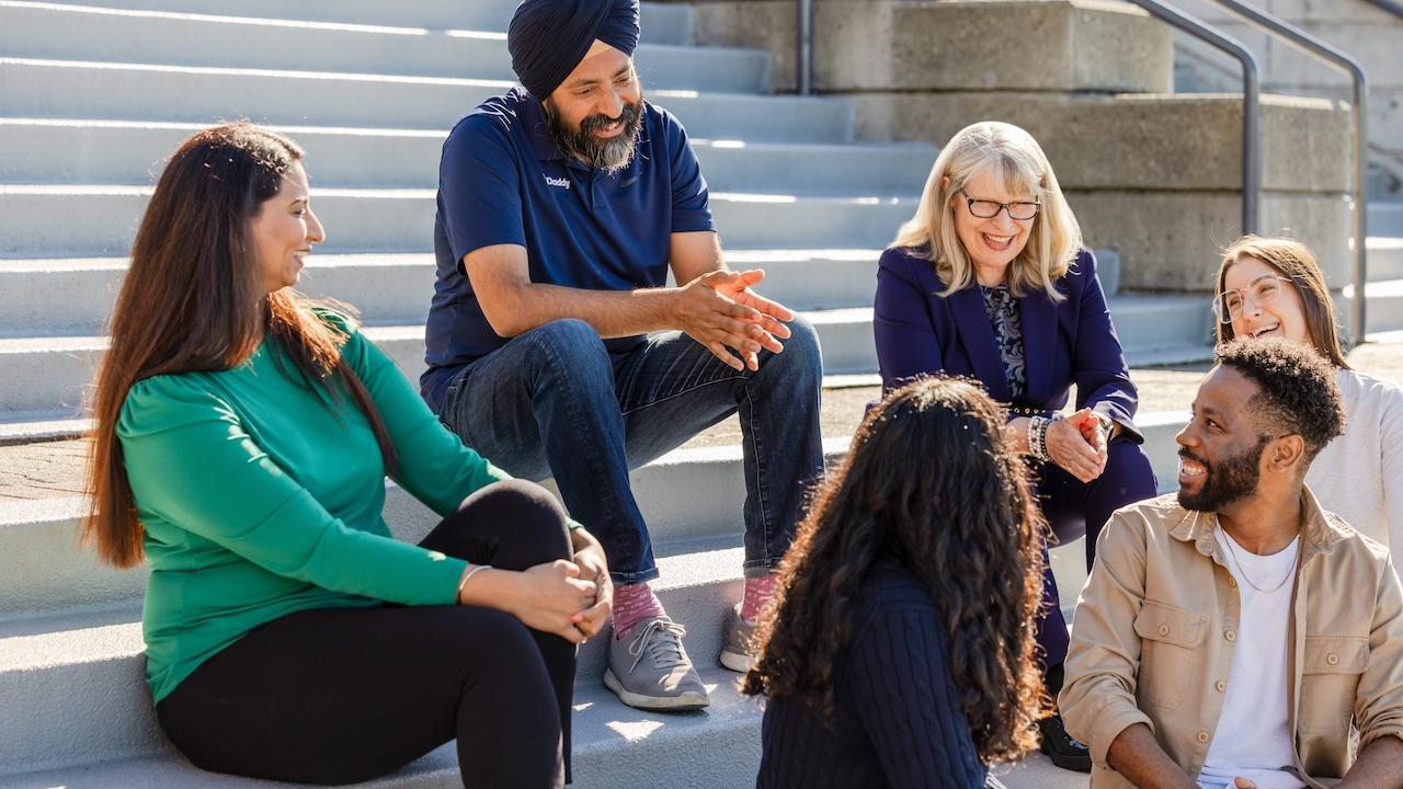 CEO Aman Bhutani shown with a group of people chatting on steps outside of a building.