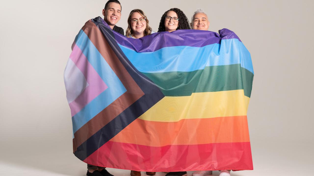 Ben C., Kat J., Jess G., & Michael G.   GoDaddy GDUnited, holding up a Pride flag.