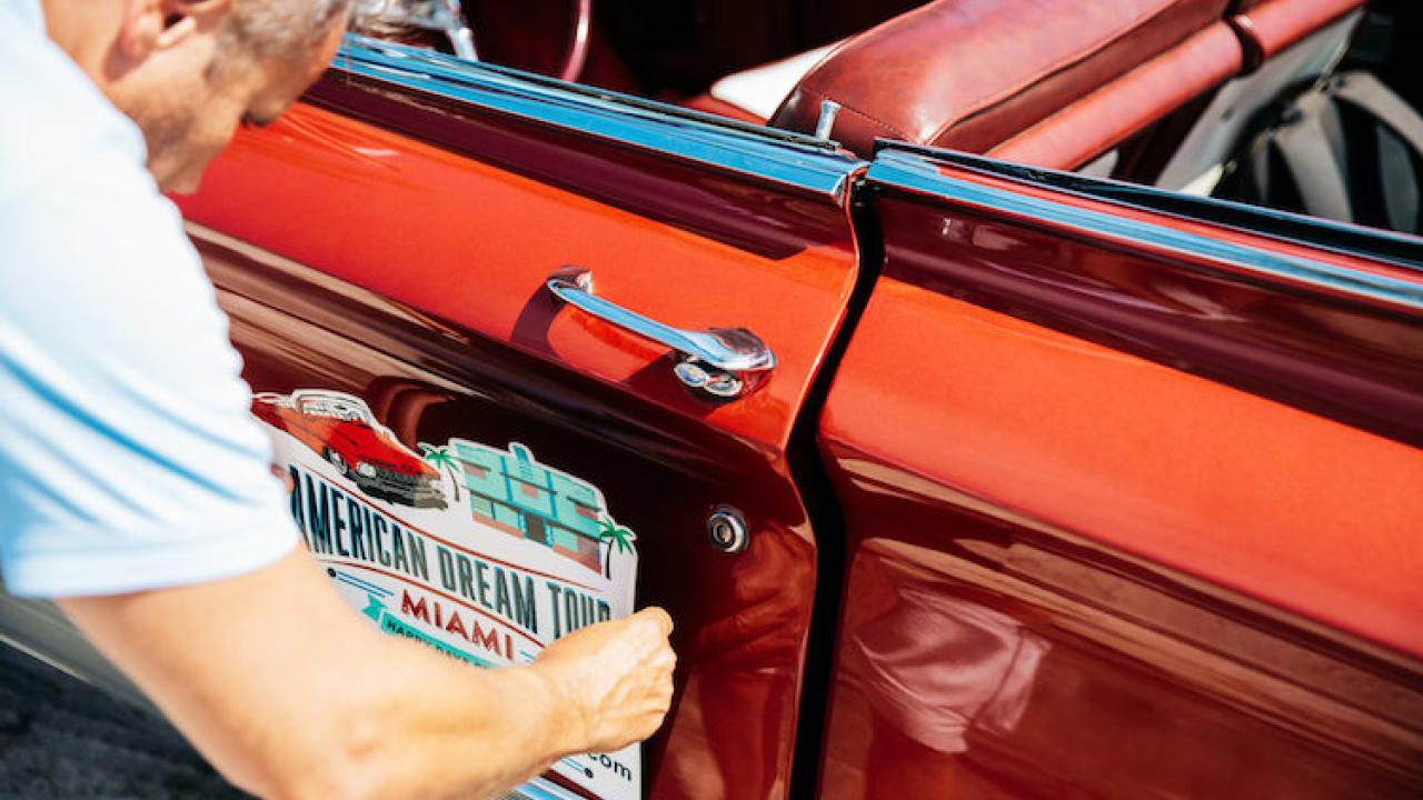 Man attaching a sign to the side of a car.