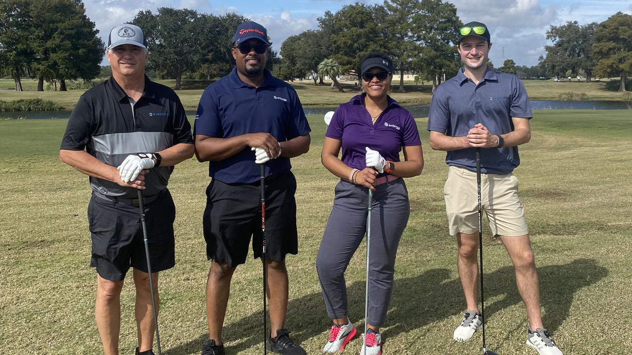 Four people holding golf clubs on a course