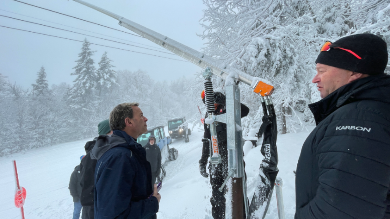 People outside on a snowy day next to snow-making equipment