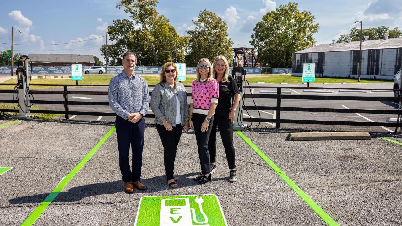 Four people stood together in an electric vehicle charger parking space 