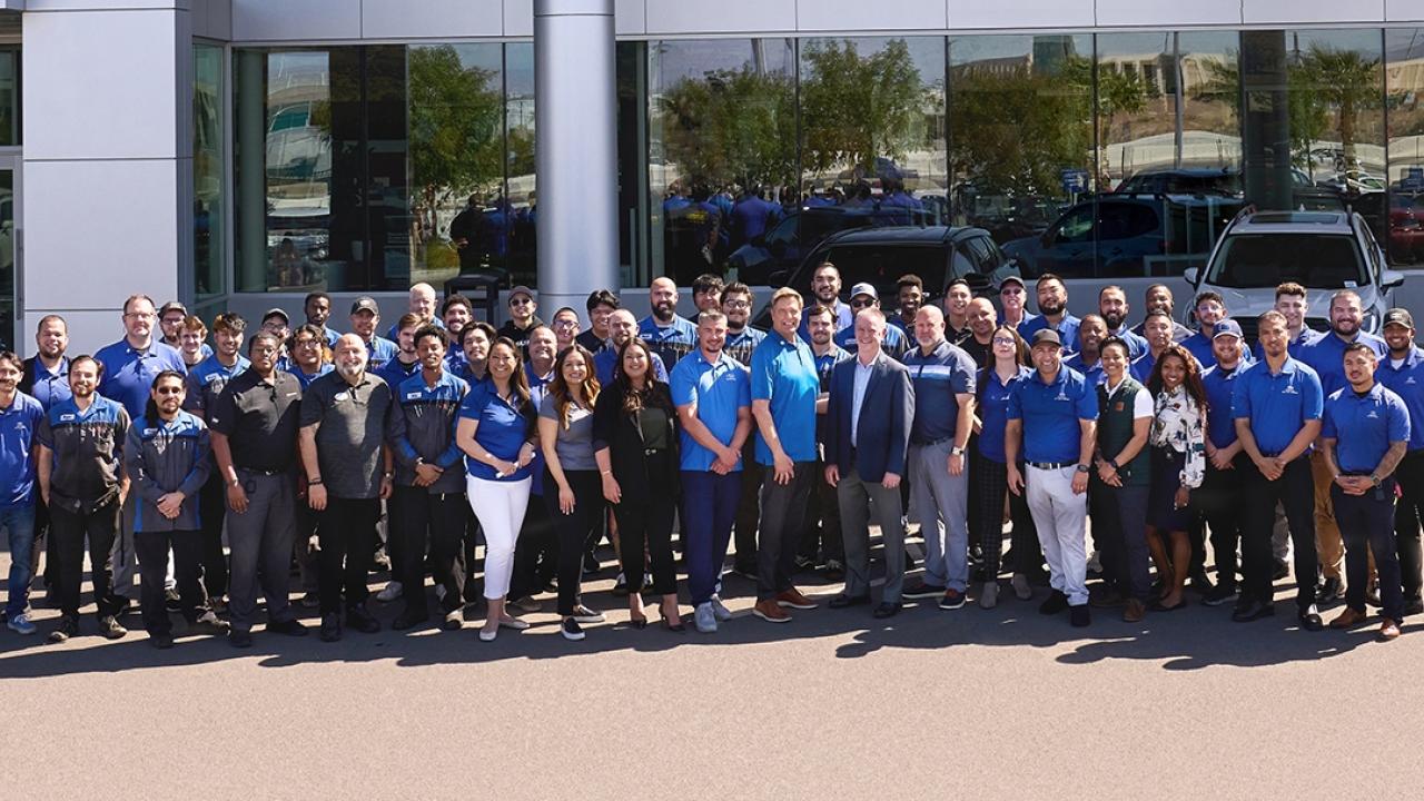 A large group photo of people stood outside a building 