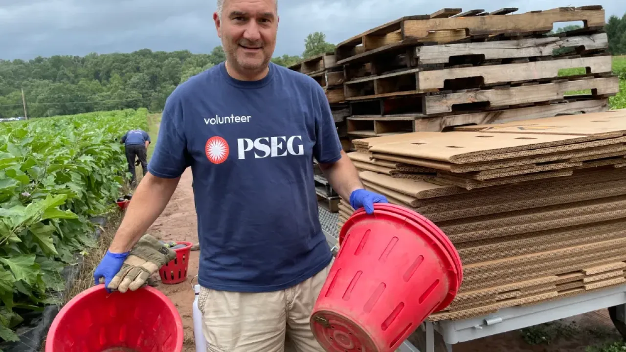 volunteer in PSEG shirt holding red buckets