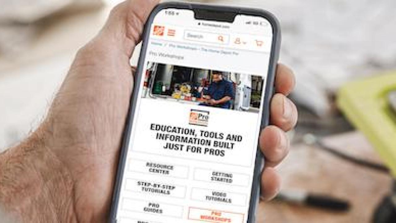 Smartphone being held in a hand; showing the Home Depot Pro Workshops app.